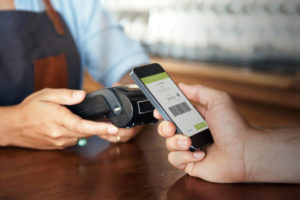 Cropped shot of a customer paying with a smartphone at a bar
